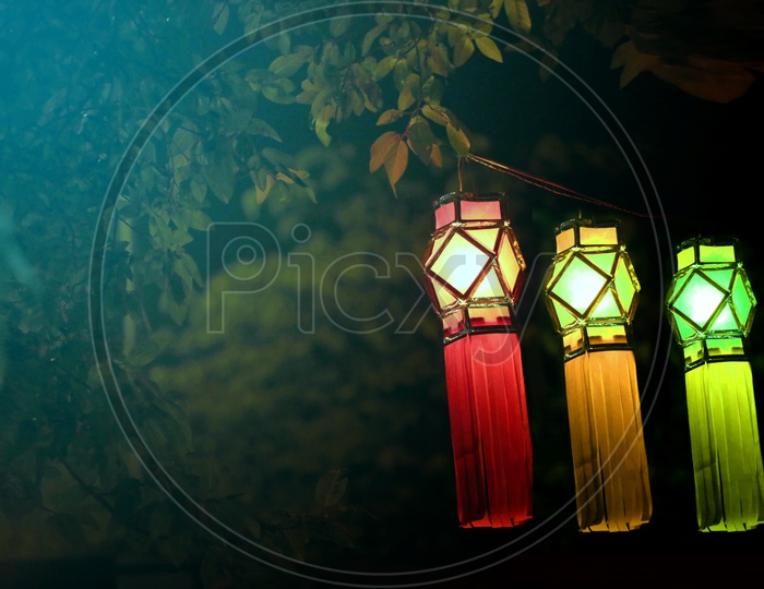 Three glowing and hanging lanterns with a dark background