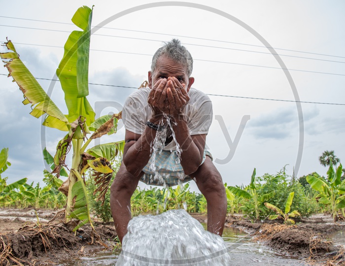 a farmer drinking water from a pumpset in a field