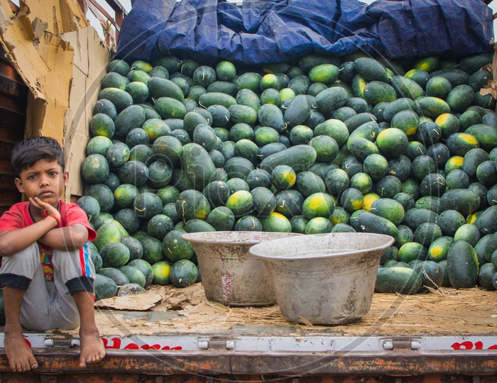 A kid watching their fresh water melon fruits arrived at market