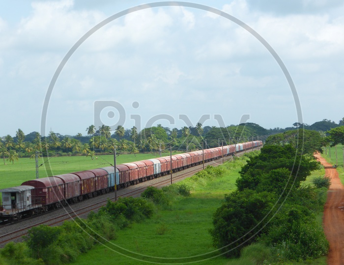 Goods Train Passing through Lush Green Agriculture Fields