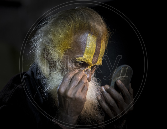 Sadhu painting his forehead  preparing himself for his daily prayers, Varanasi