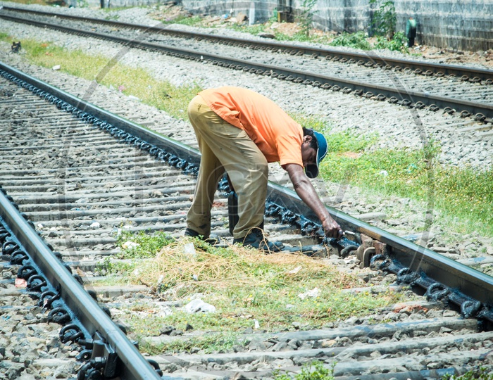Railway maintenance worker painting and greasing railway tracks