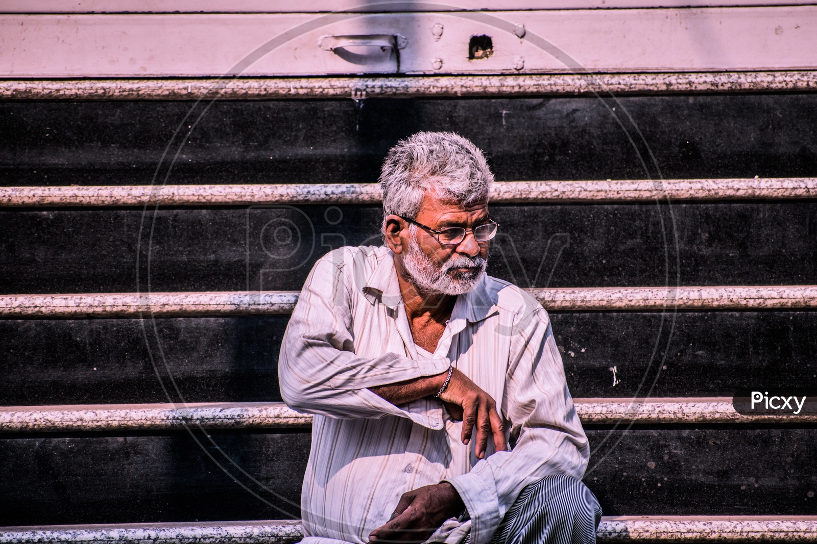 A old  man posing in the streets behind the leading lines with hand inside is shirt pocket.