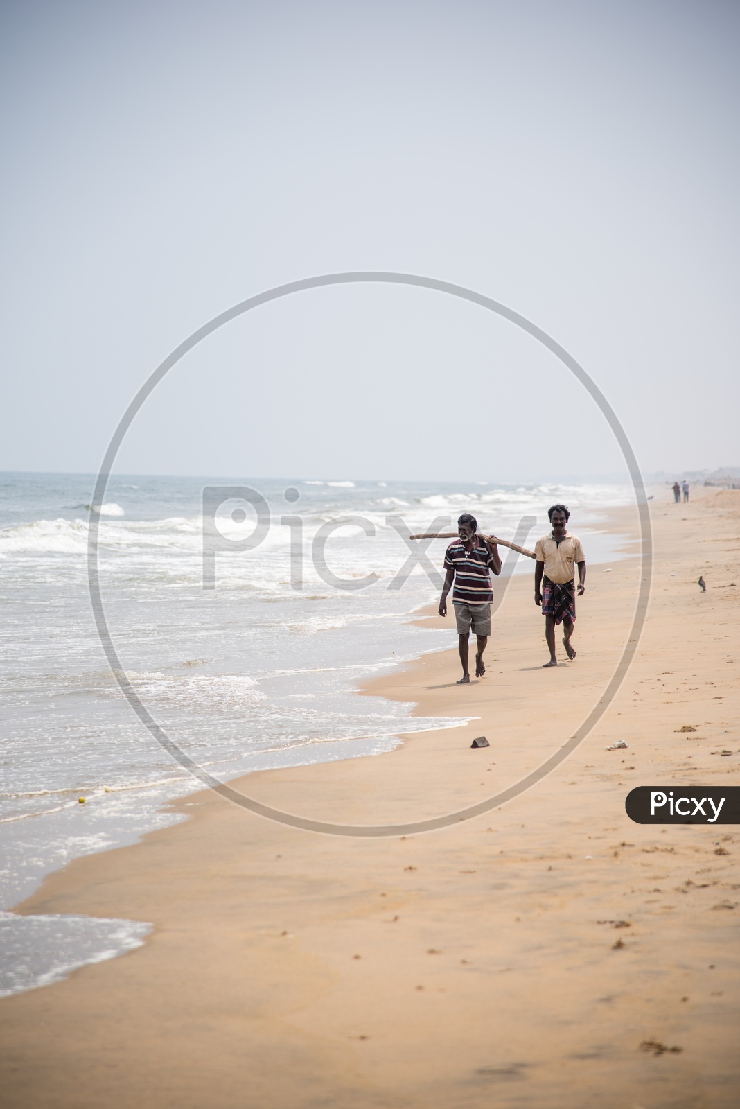 A couple of Fishermen walking across the Tiruvanmiyur Beach