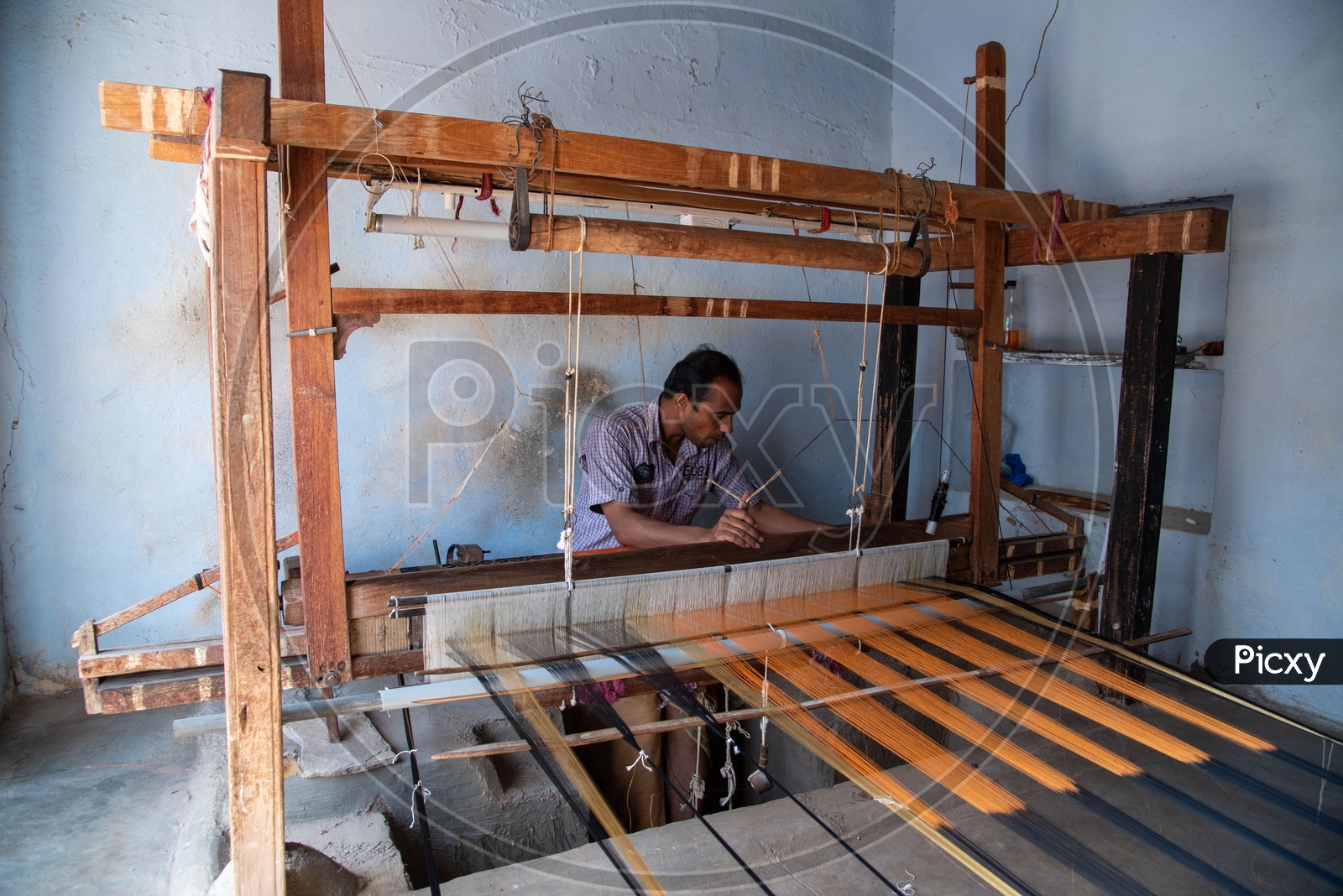 Artisan works on making sarees on hand operated weaving spindle in Pochampally