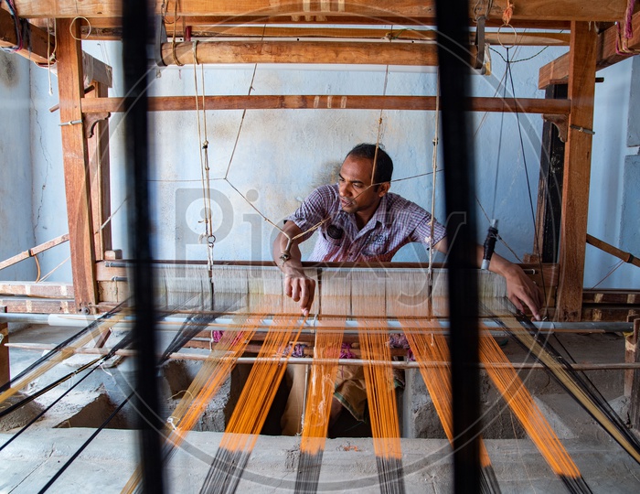 Working weaving the threads to make Ikkat saree on a weaving spindle