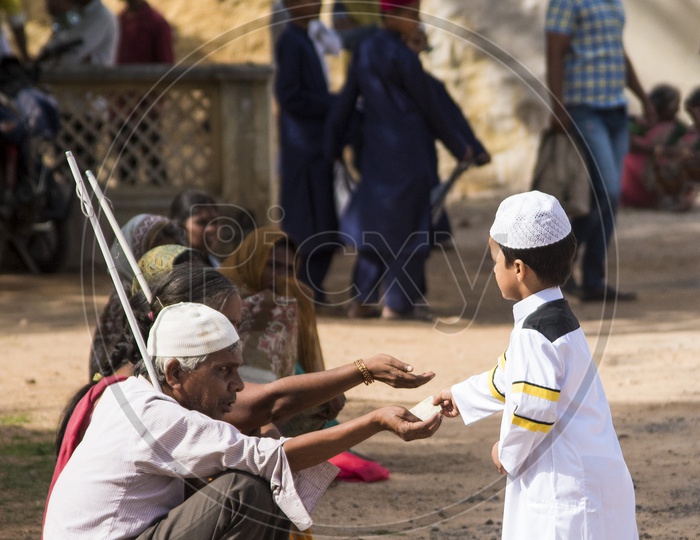 Kid giving alms to the needy at Eid Prayer meet at Qutb Shahi Tomb