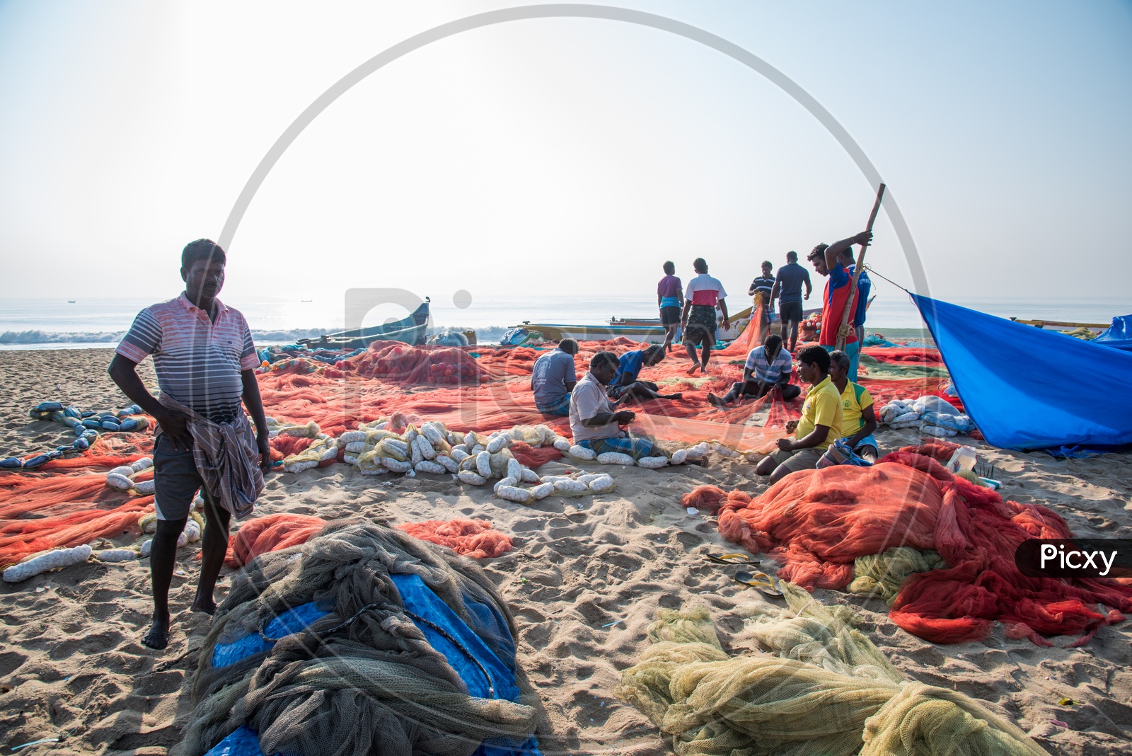 Fishermen Sewing their fish nets after a fishing session