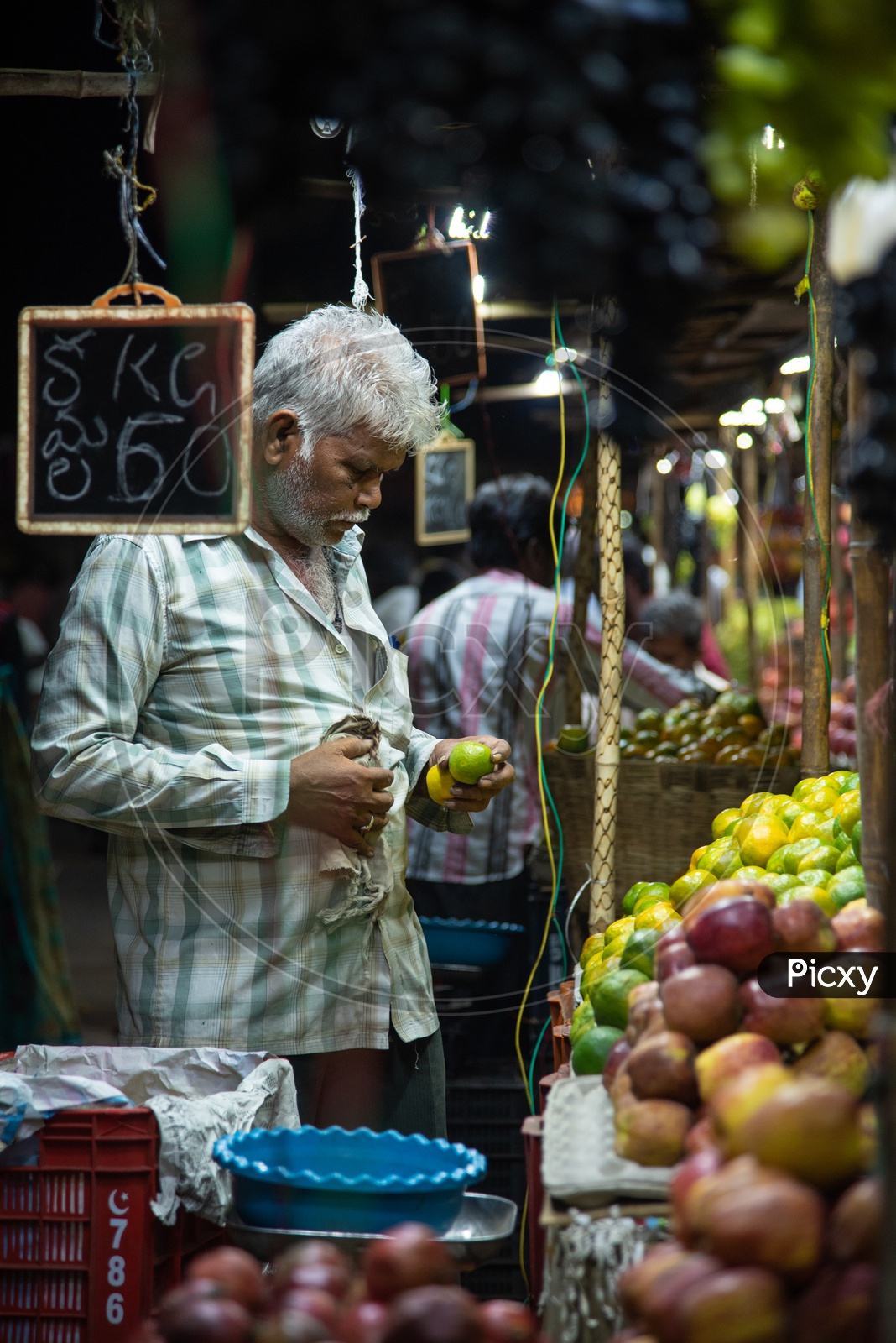A fruit vendor inspecting his fruit stock as he puts them for sale.