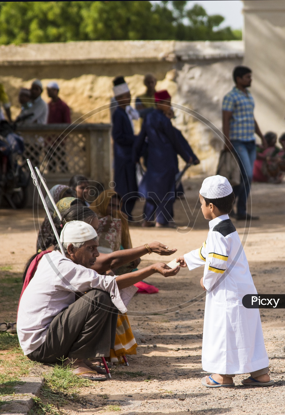 Kid giving alms to the needy at Eid Prayer meet at Qutb Shahi Tomb