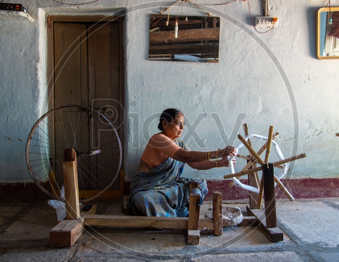 Lady working on a spindle wheel in a village in Pochampally