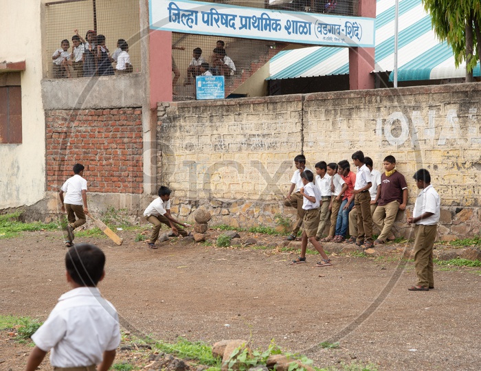 Kids playing cricket in a school playground in Wadgaon Shinde