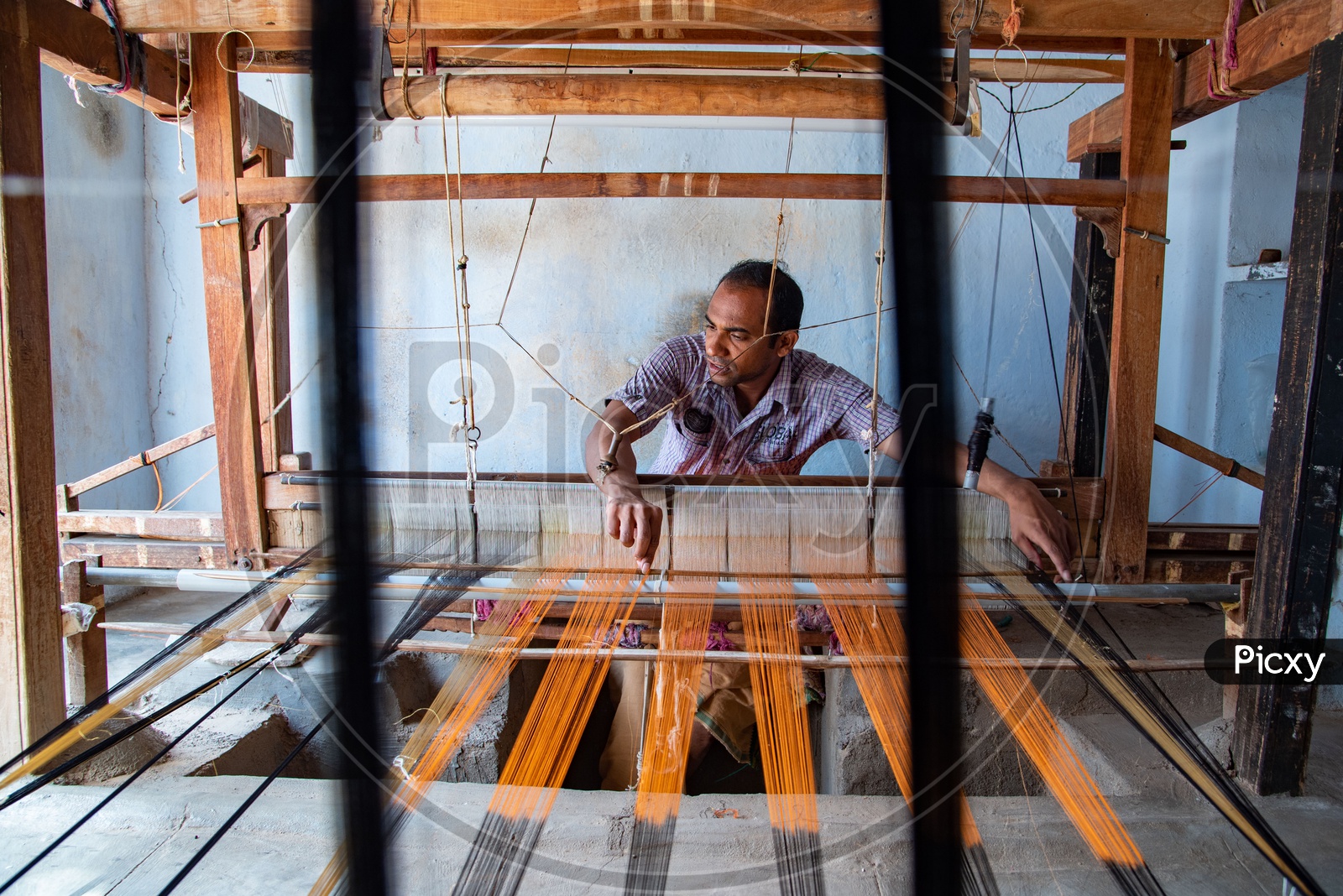 Working weaving the threads to make Ikkat saree on a weaving spindle