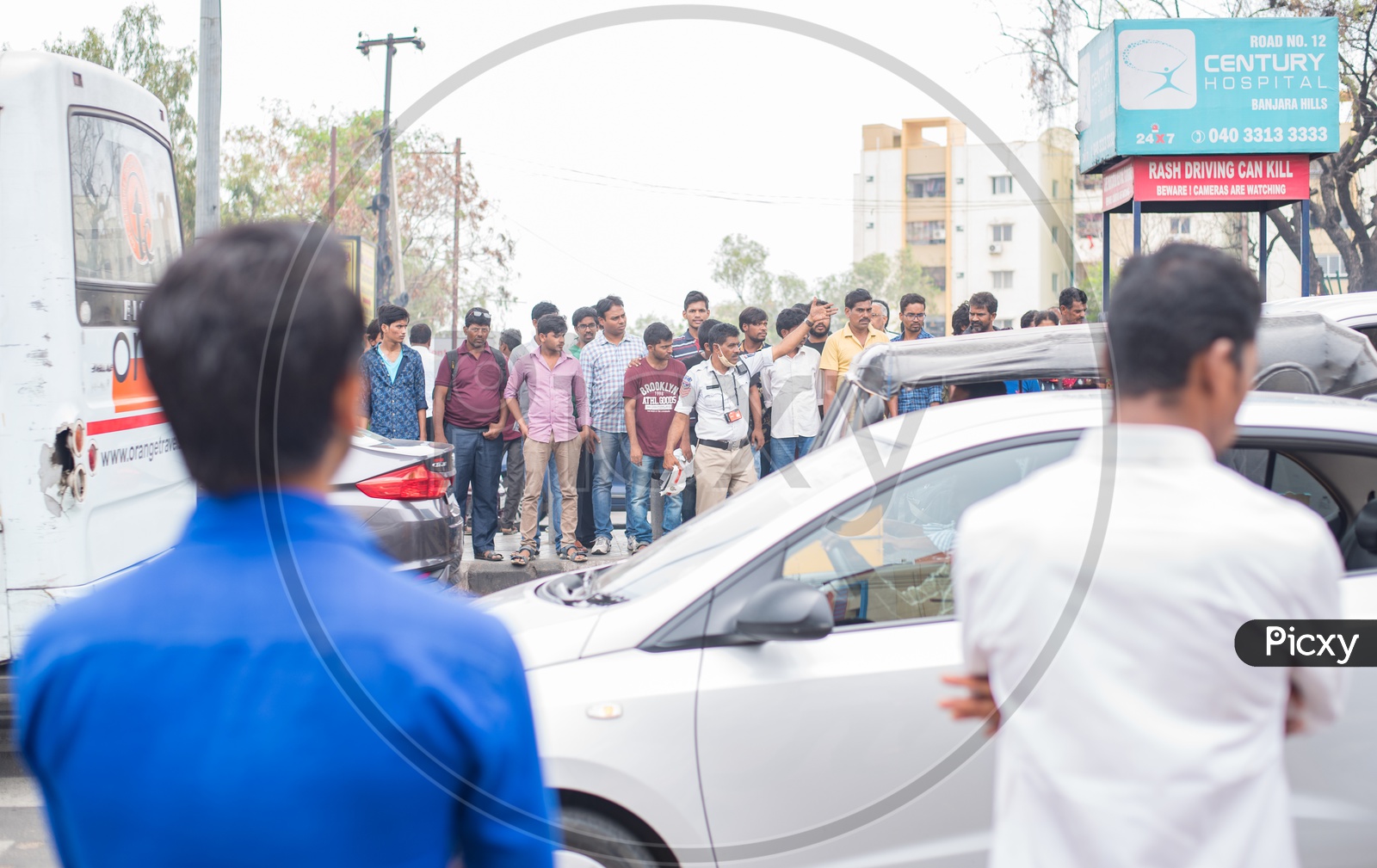 a traffic constable controlling traffic as people wait for their turn to cross the road .