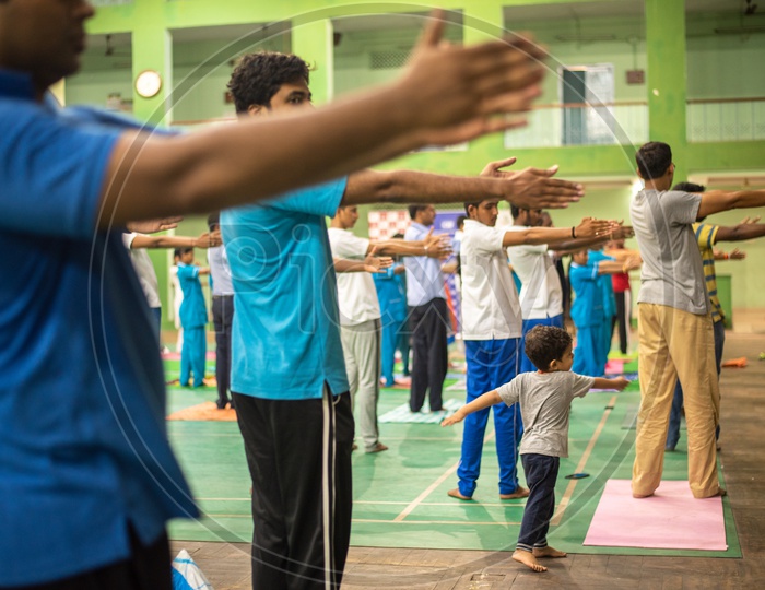 a kid playing around while adults practice Yoga, International Yoga Day, 2018.