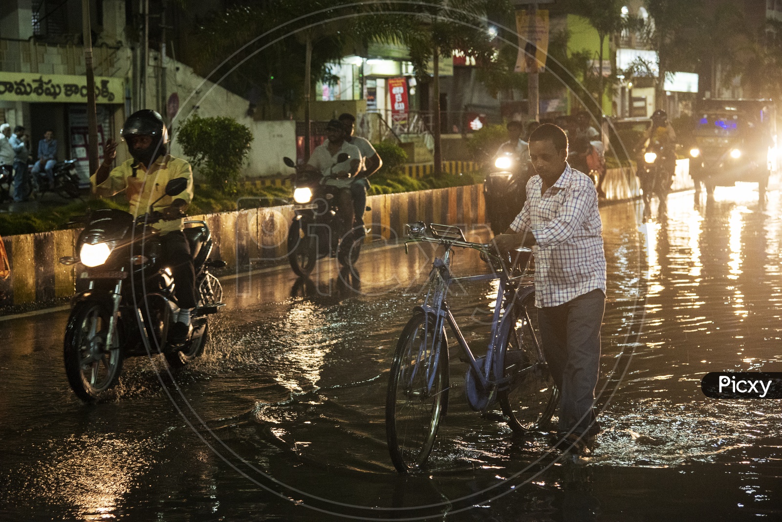 A man crosses a waterlogged road with a bicycle  in Vijayawada after a heavy rain on 03/05/18