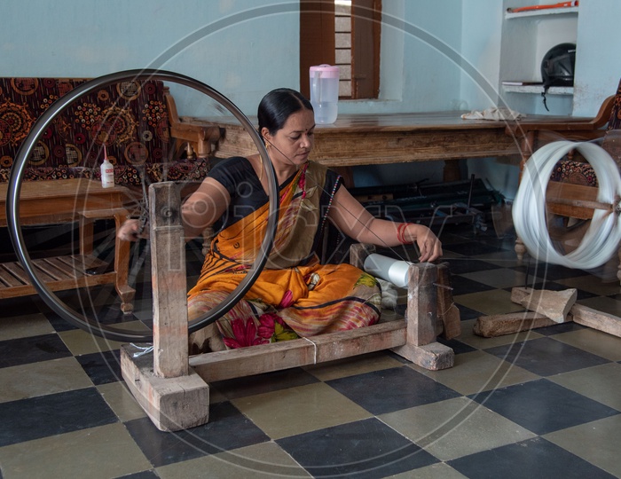 Lady working on spinning wheel to make thread