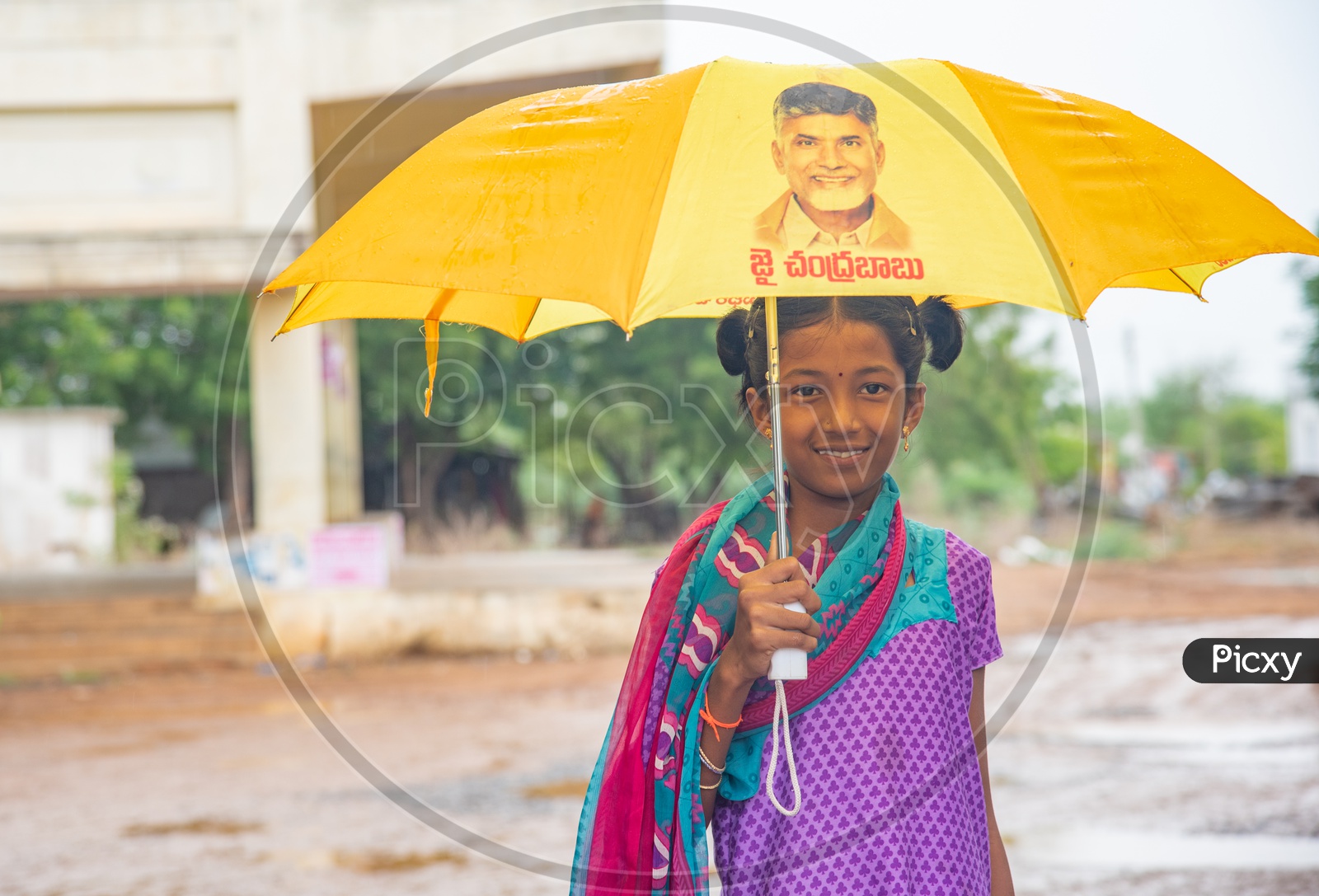 A girl carrying an umbrella with AP Chief Minister's image on it