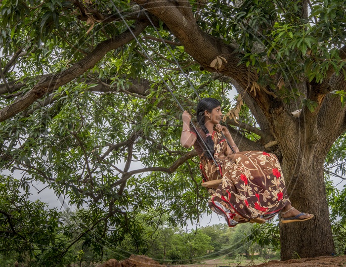 Village girl swinging on a swing made of a Tyre