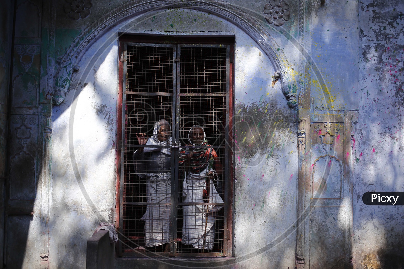 Women look out from an netted door inside an ashram in Vrindavan