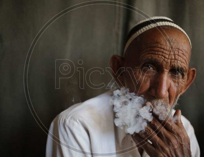 An elderly man looks on while smoking a bidi in the old quarters of Delhi