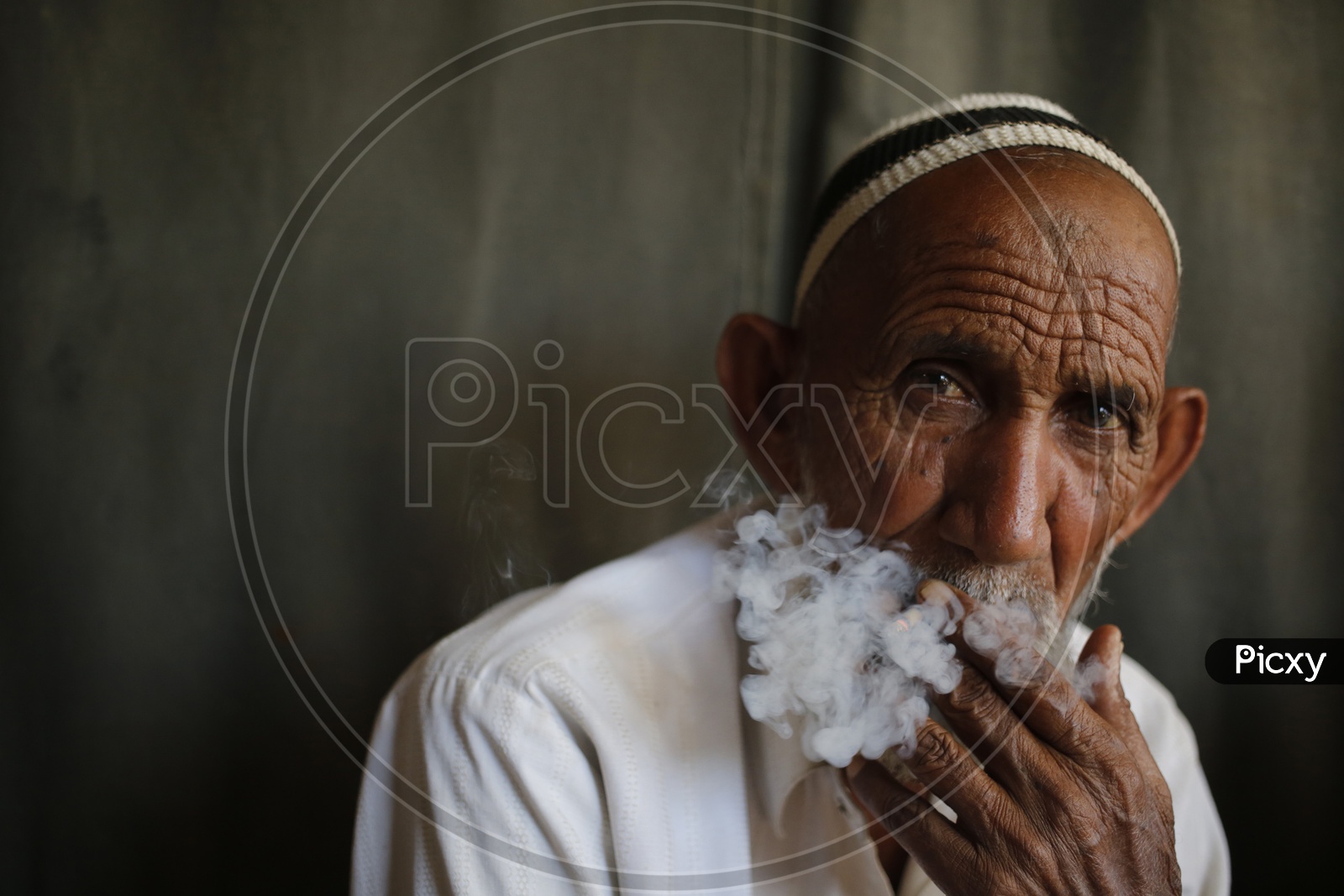 An elderly man looks on while smoking a bidi in the old quarters of Delhi