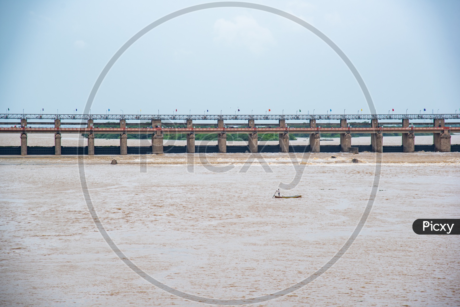 A fisherman rows his boat against the current of water at prakasam Barrage after the surplus water has been released into the sea