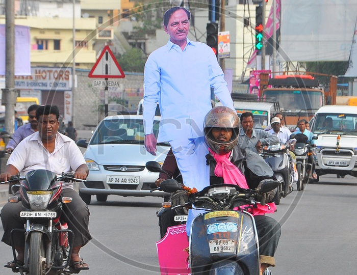 A TRS Supporter taking CM KCR Hoarding on Bike in Hyderabad