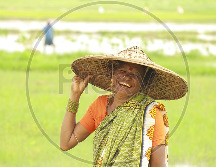 Smiling woman wearing Hat in Paddy Fields, Odisha