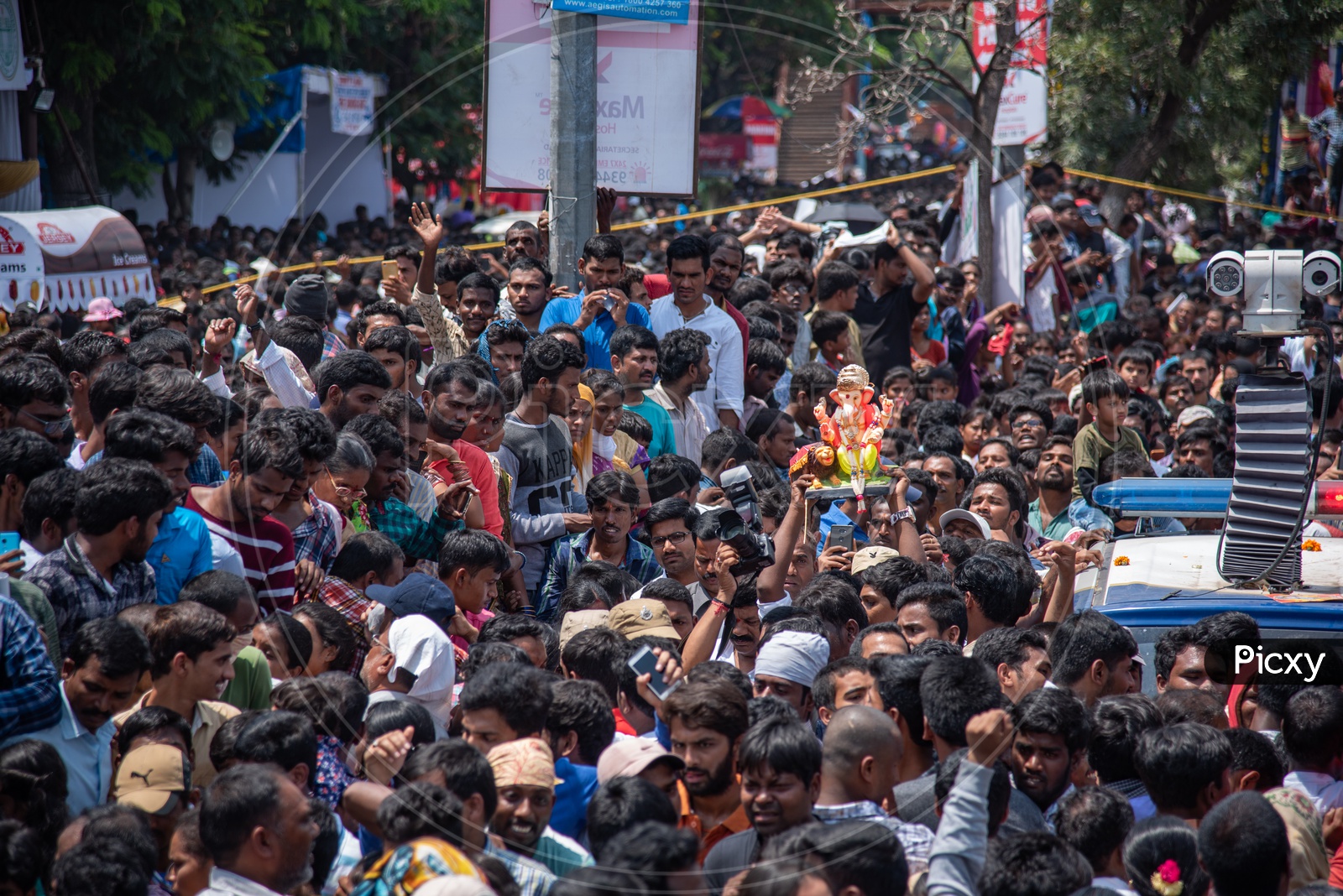 A small ganesh idol being carried by a devotee among humongous crowd