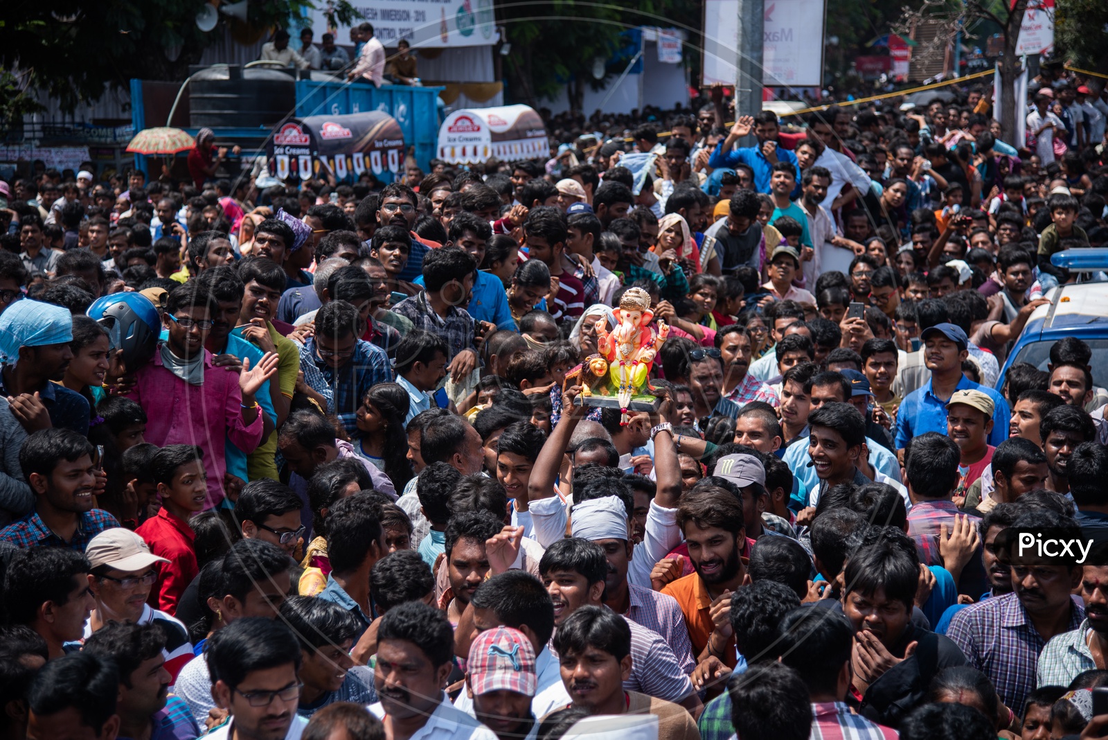 A small ganesh idol being carried by a devotee among humongous crowd