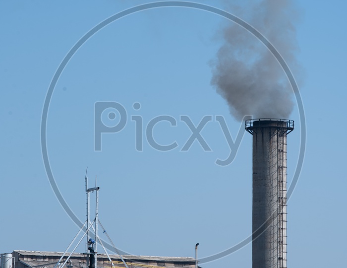 A Thick Black Smoke Coming Out Of a Industrial Exhaust Pipe from a Sugar Factory