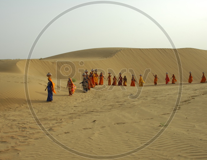 Indian women carrying water pots in Rajasthan desert.