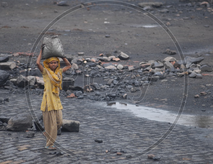 A girl carrying Coal in sack in a Coal mine