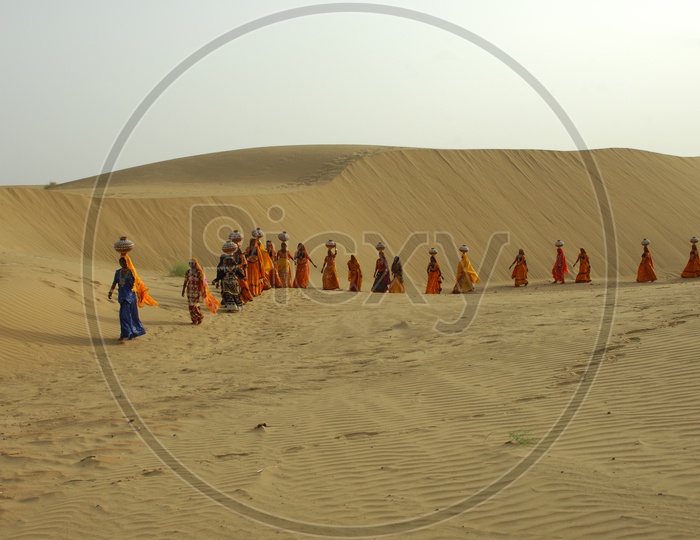 Indian women carrying water pots in Rajasthan desert.