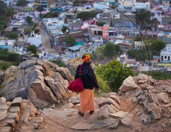 An Indian Sadhu / Baba At a Hill Top With Houses On The Background