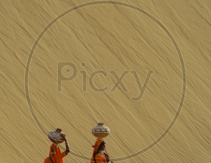 Rajasthani Women carrying water pots on their head in a Desert