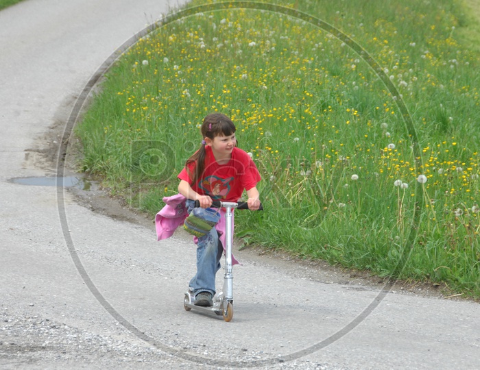 Girl Child Playing With a Skateboard Bike