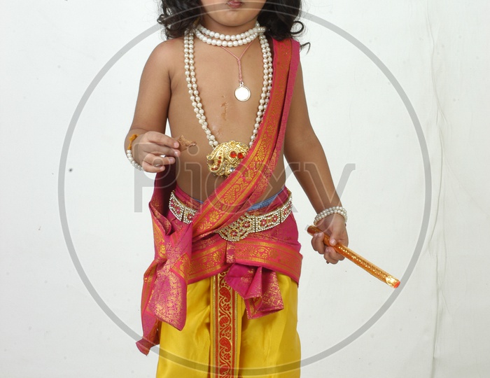 Indian Boy in Lord Sri Krishna Getup  and eating Chocolate Over an isolated White Background