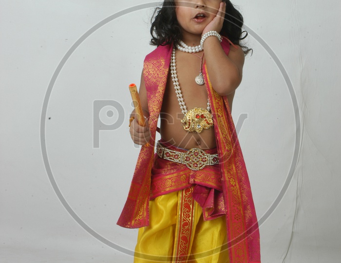 Indian Boy in Lord Sri Krishna Getup  and Eating Chocolate Over an isolated White Background