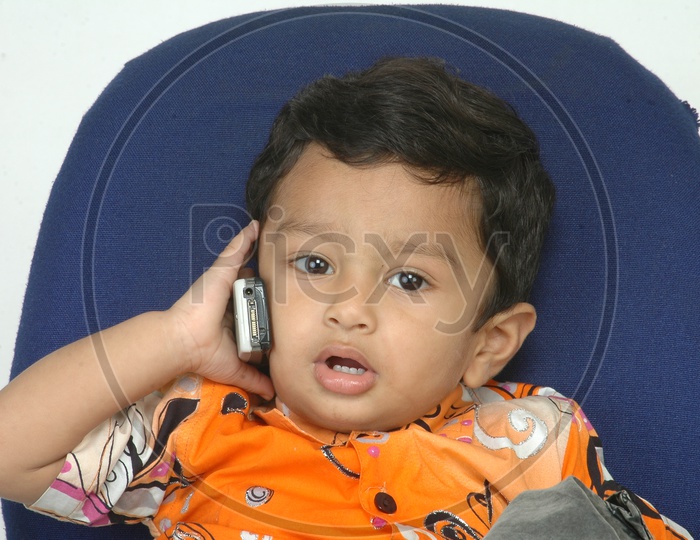 Indian Baby Boy Playing with Cellphone Closeup Shot On an Isolated White Background