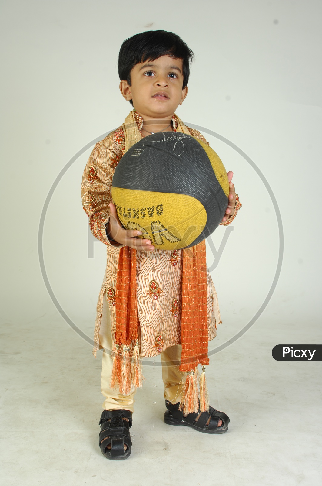 Indian Boy in Traditional Clothes With a Smiling Face  and With a Basketball in Hand  Over an Isolated White Background