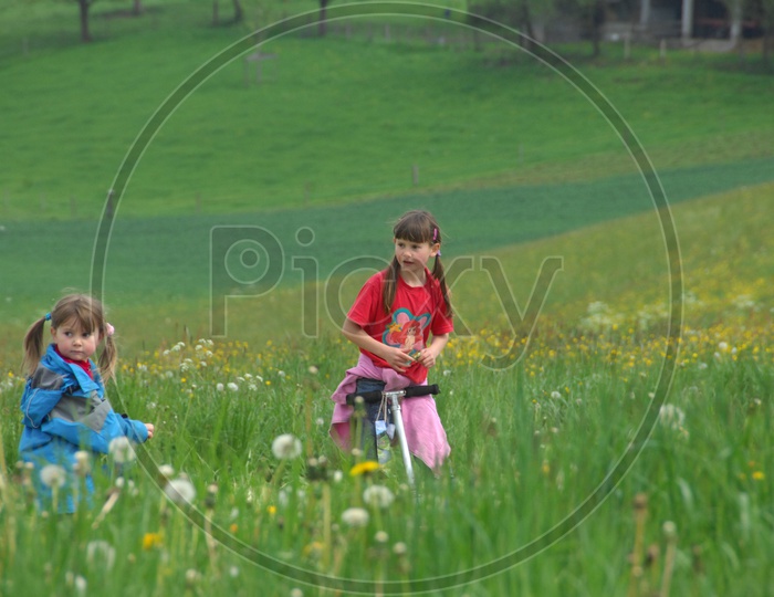 Two Foreign Children With Skateboard Bike In a Garden