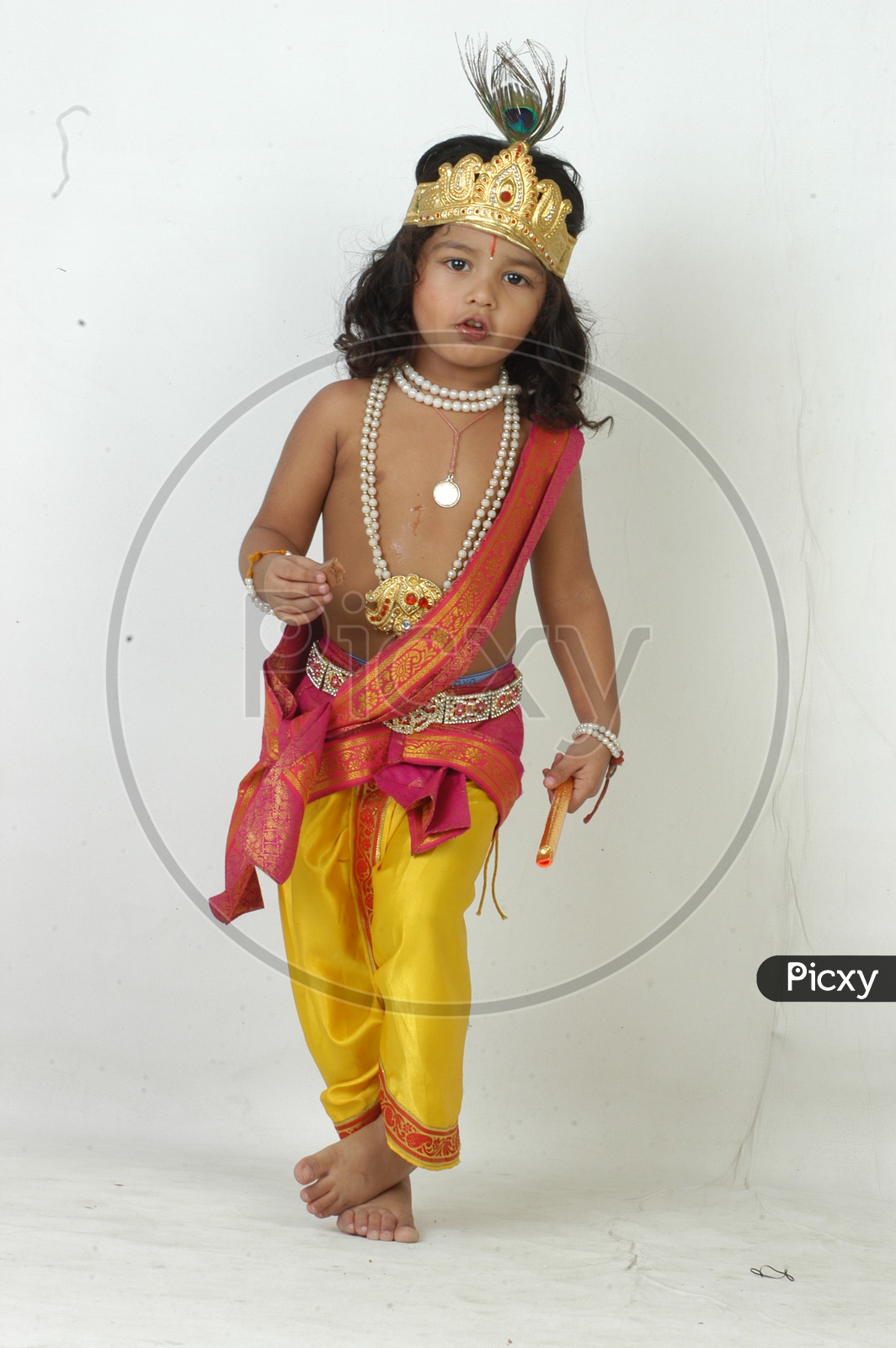 Indian Boy in Lord Sri Krishna Getup  and eating Chocolate Over an isolated White Background