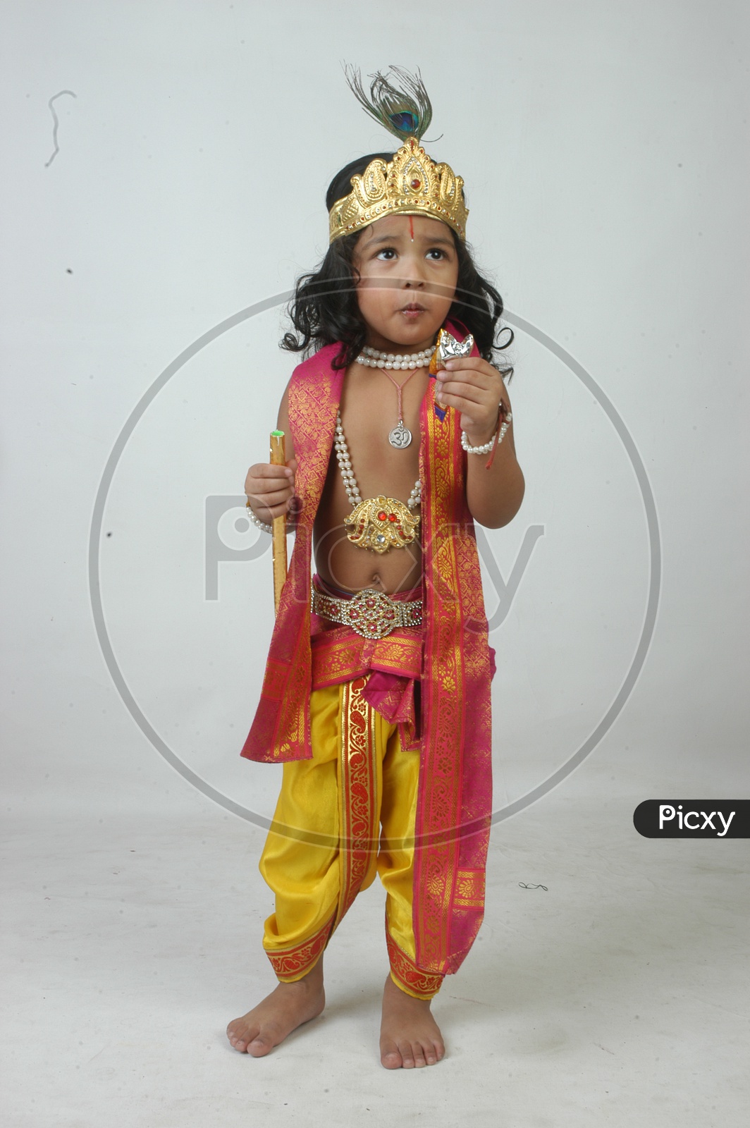 Indian Boy in Lord Sri Krishna Getup  and Eating Chocolate Over an isolated White Background