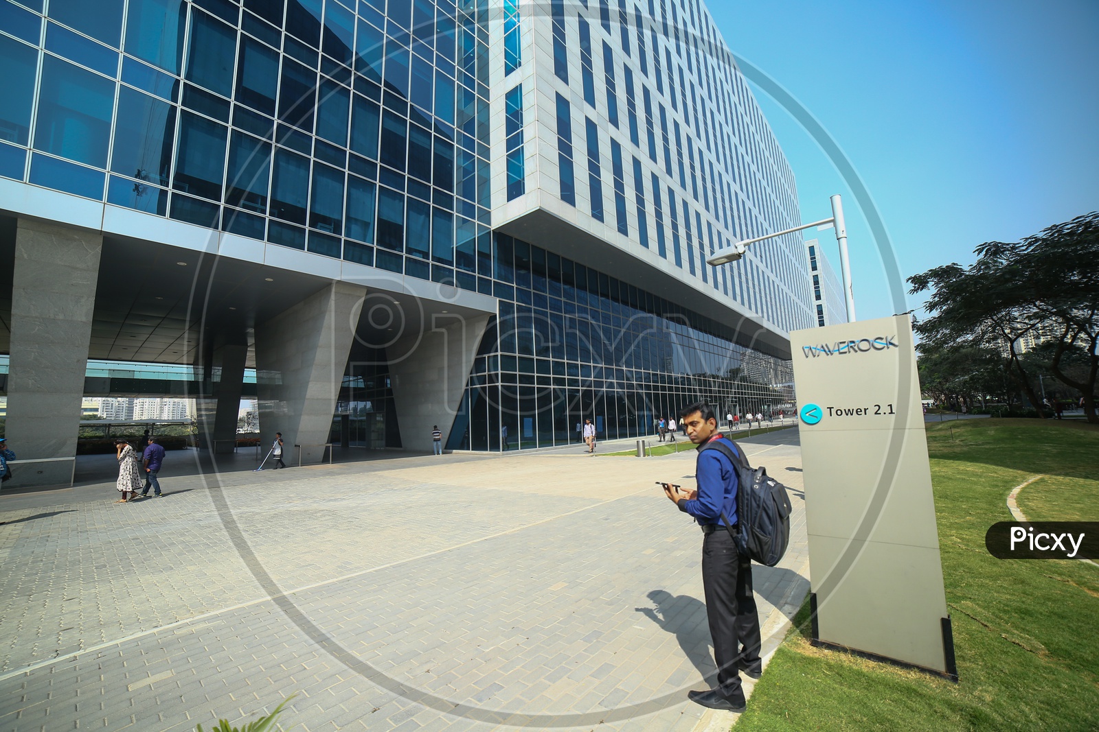 A Beautiful Architectural View Of WaveRock SEZ Building In Hyderabad with IT Employees walking in the Campus