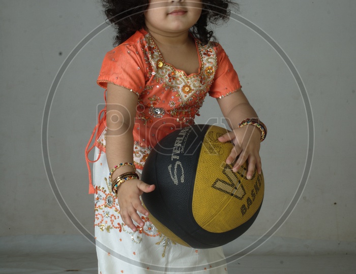Indian Girl kid in a studio playing with basketball