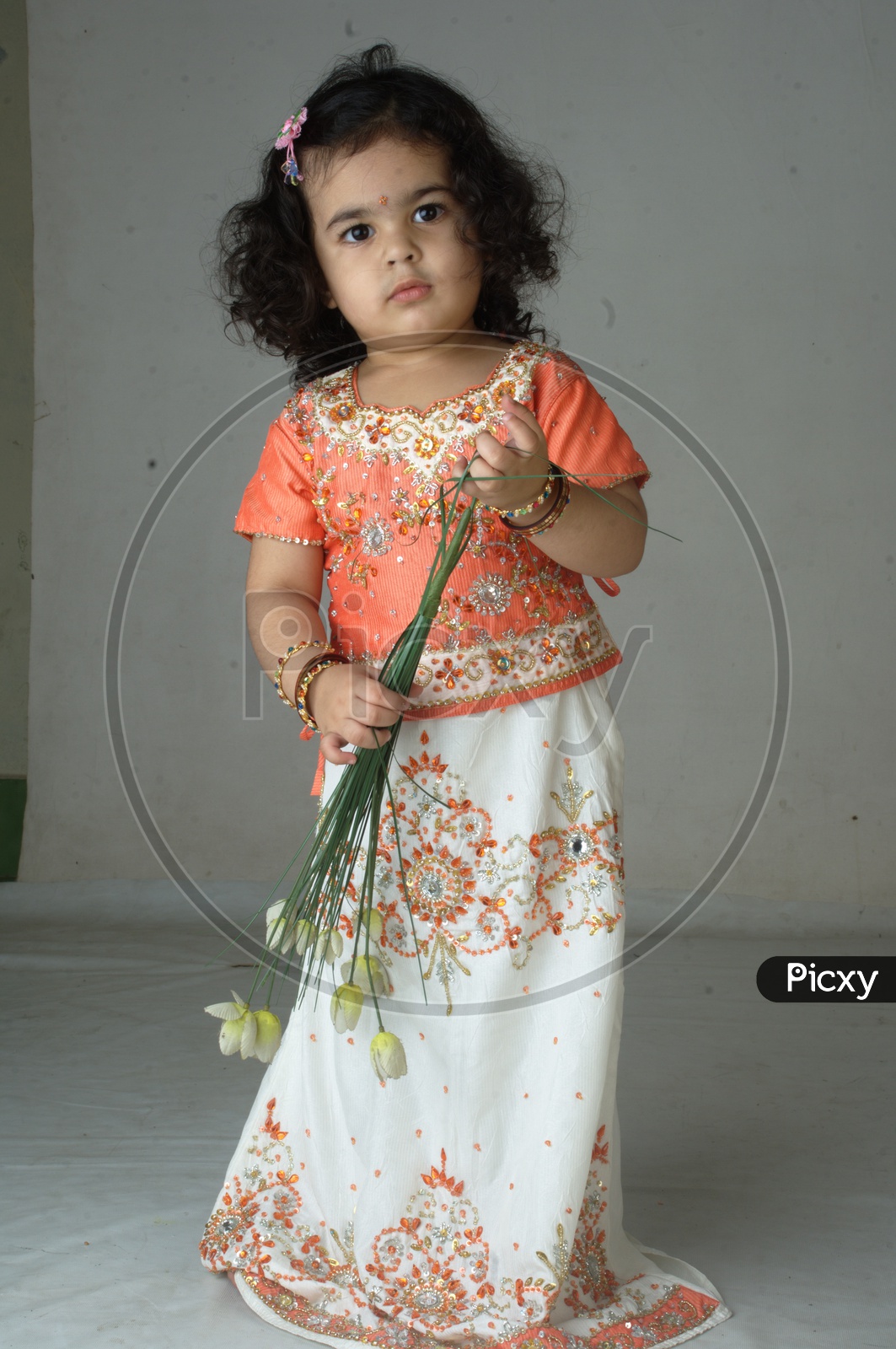 Indian Girl kid in a studio playing with plastic flowers