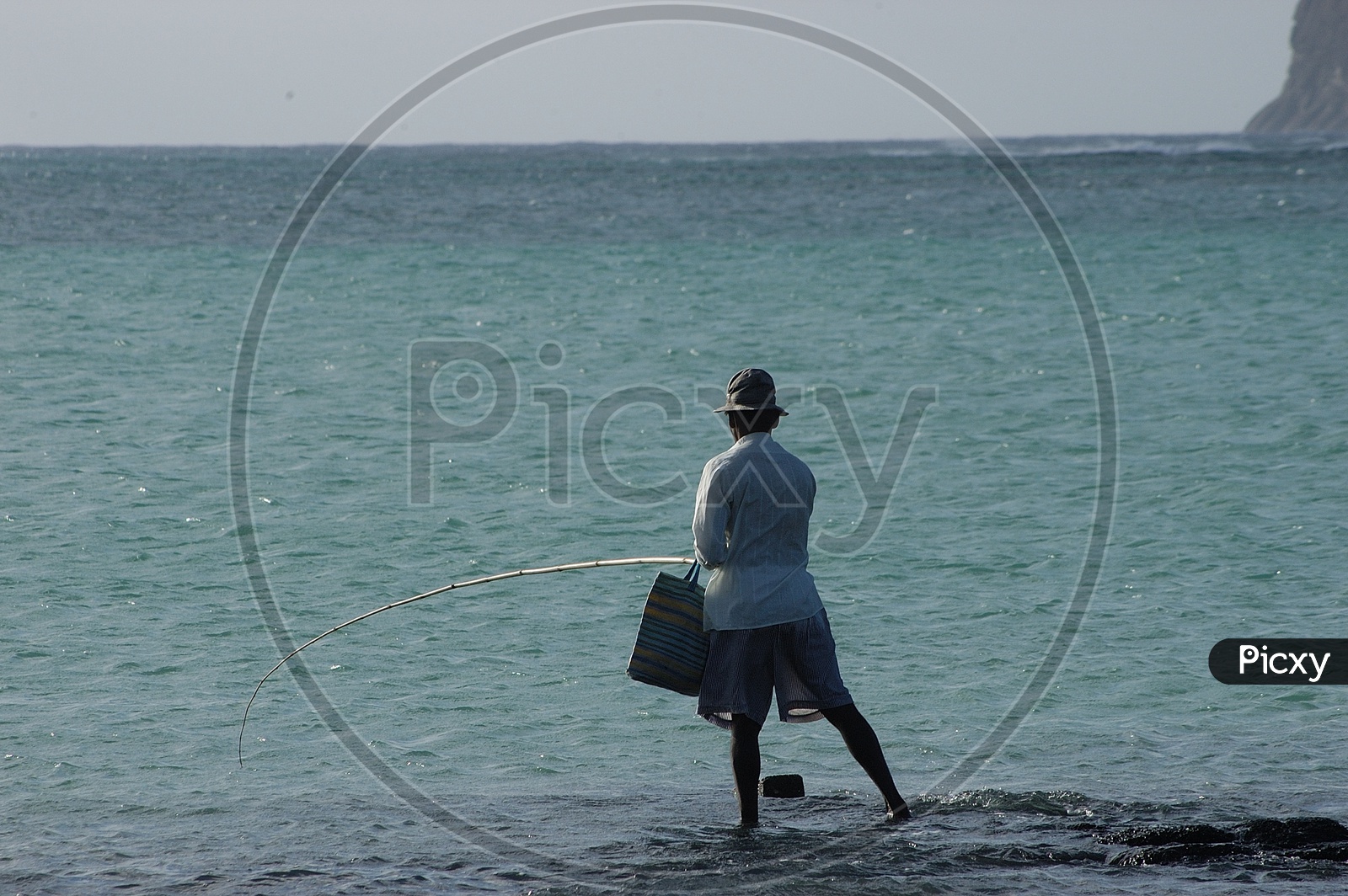 A Fisher Man Fishing With Fishing Road on a Beach