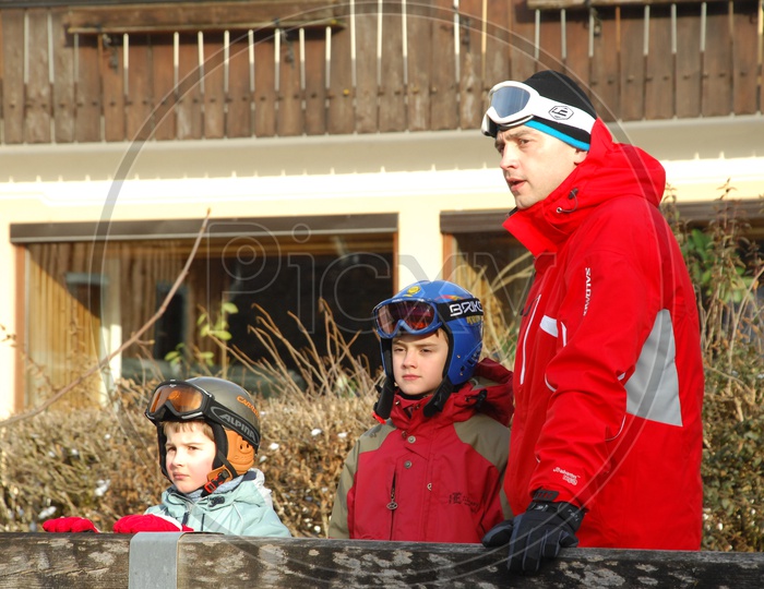 A Father and His Daughters In Snow Skiing Suits